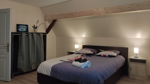 A bedroom with a bed, two bedside tables, a nightstand, a wardrobe, and a ceiling light fixture.