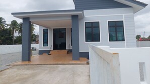 A modern two-story house with a covered porch, large windows, and a sloped roof.