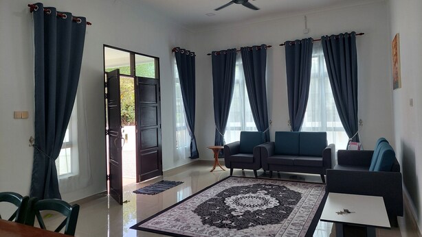 A spacious living area with a sofa set, a coffee table, and a patterned rug.