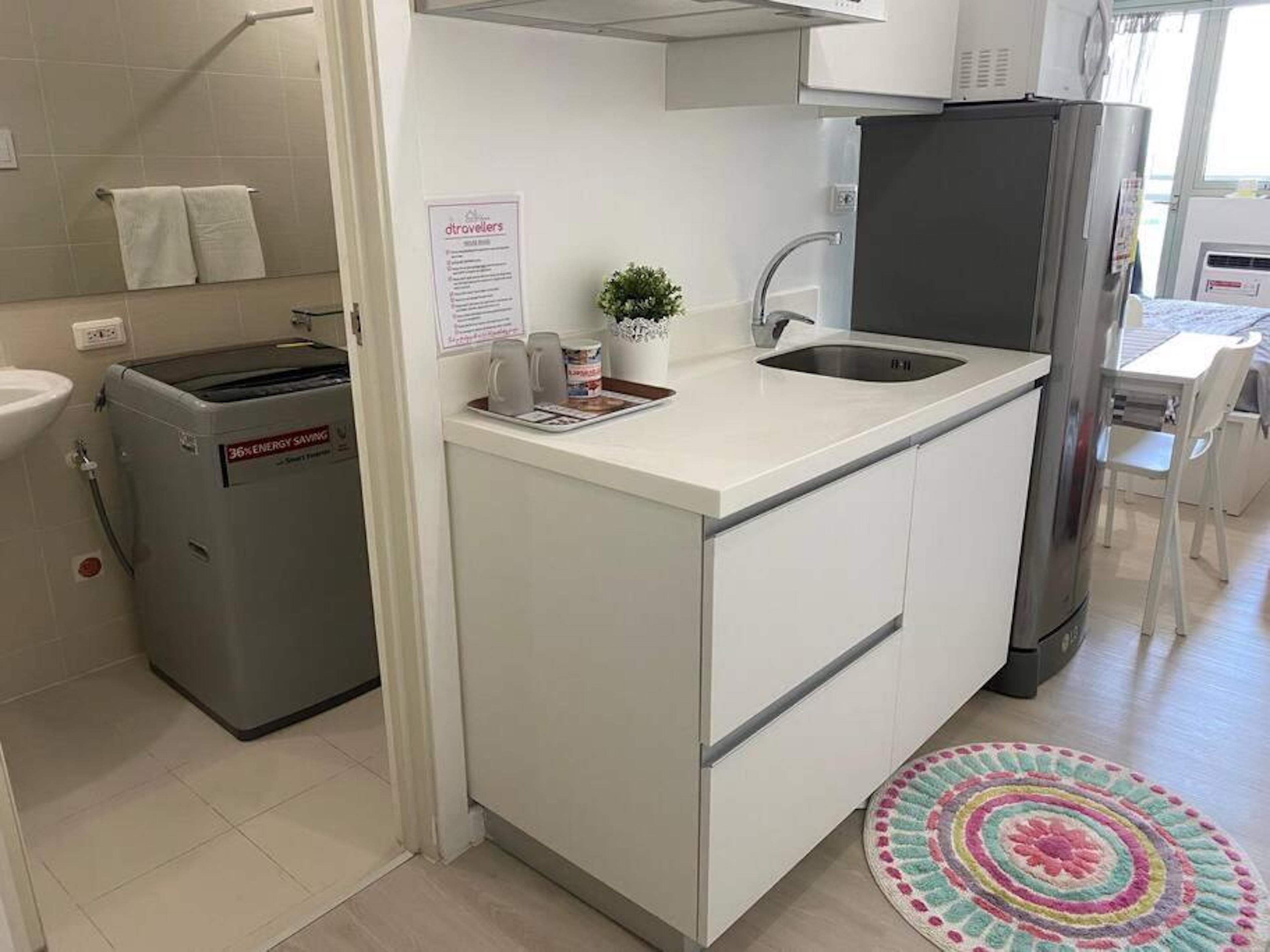 A compact kitchen with a built-in sink, a small refrigerator, and a compact washing machine.