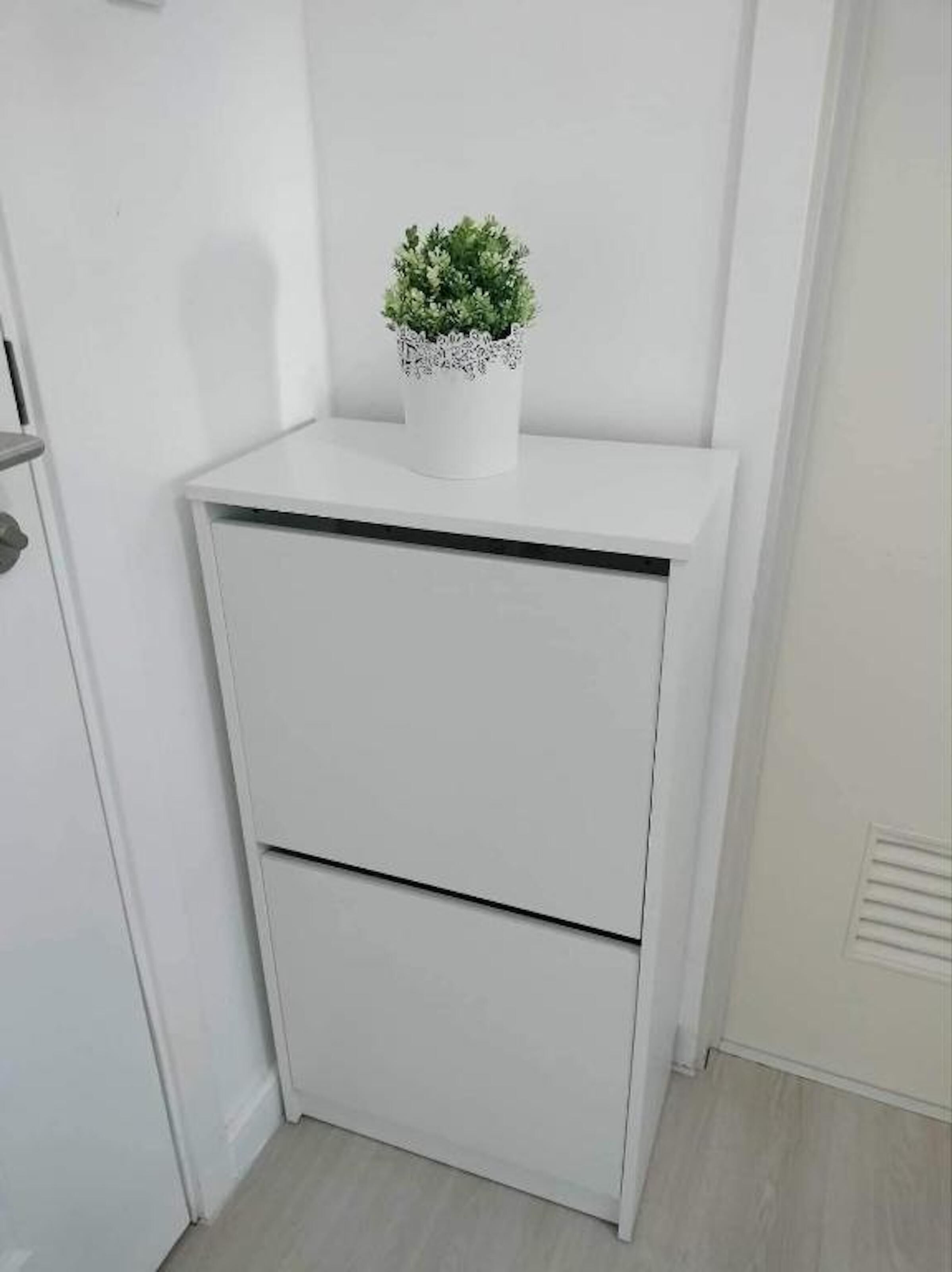 Et hvidt skab med en lille potteplante ovenpå.