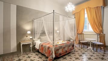 A bedroom with a four-poster bed, a bedside table with a lamp, a chair, and a small round table.