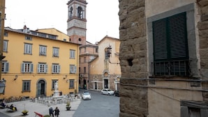 A narrow street with yellow buildings, a bell tower, and a sign reading "Via Calberia". - Residenza Centro Storico (Lucca)