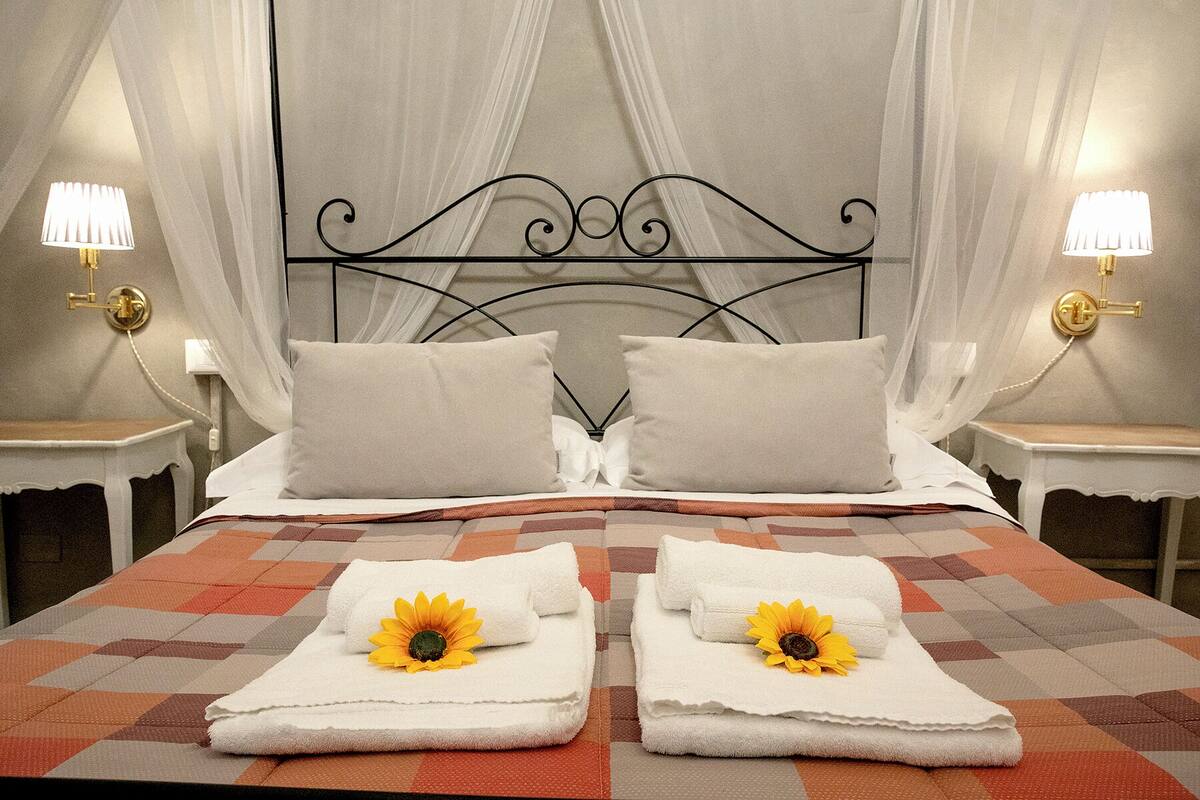 A double bed with a checkered bedspread, two pillows, and two towels with sunflowers.