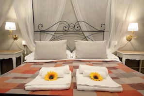 A double bed with a checkered bedspread, two pillows, and two towels with sunflowers. - Residenza Centro Storico (Lucca)
