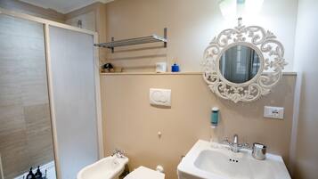 Un baño con ducha, inodoro, lavamanos y espejo.