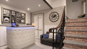 A reception area with a tufted desk, a clock, and a staircase. - Residenza Centro Storico (Lucca)