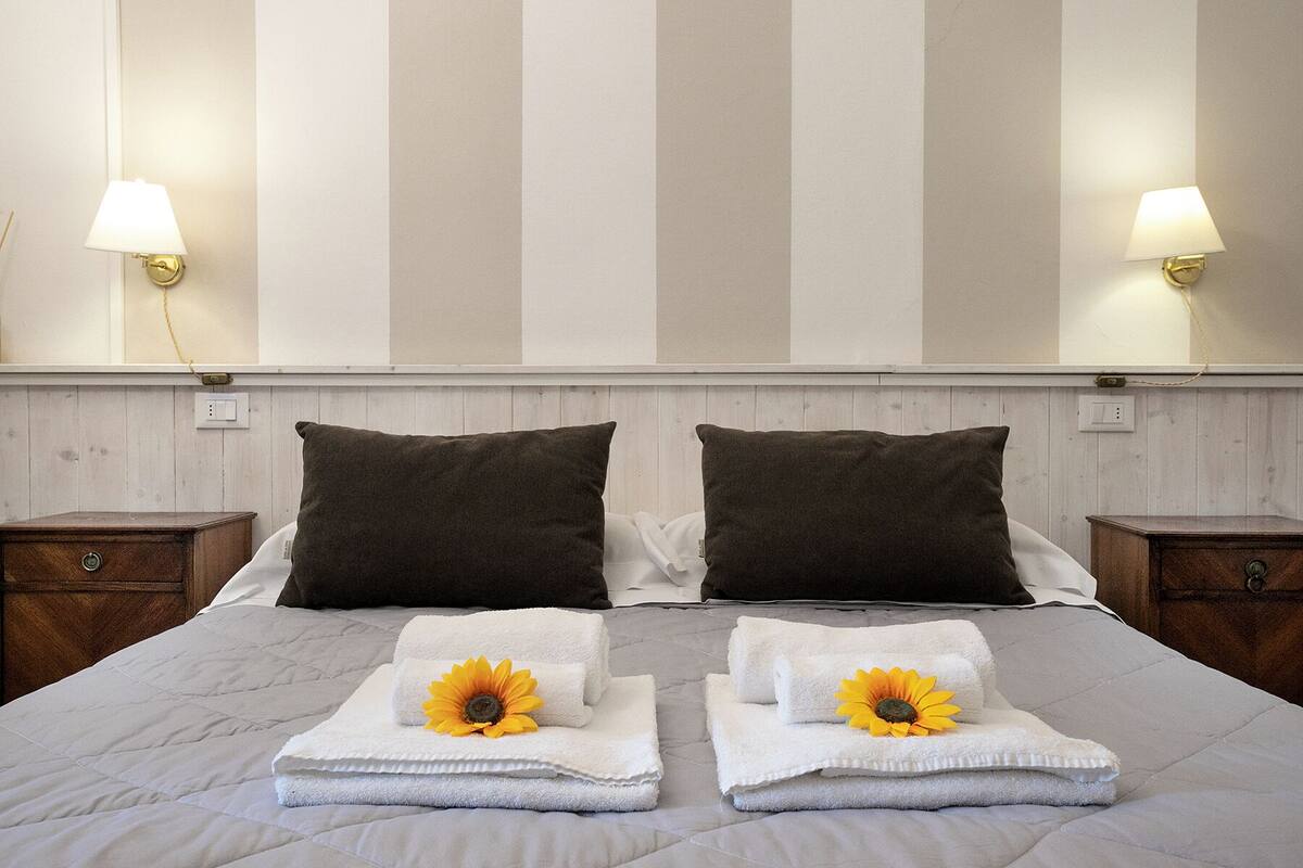 A hotel room with a bed, two nightstands, and a wall with vertical stripes.