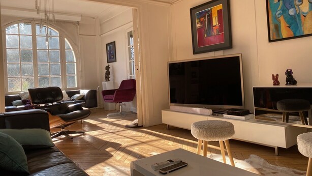 Un salon doté d’un grand téléviseur, de canapés en cuir, d’une table basse blanche et d’œuvres d’art accrochées aux murs.
