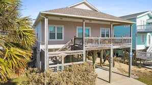 A two-story house with a balcony, a covered porch, and a small deck. - Ginger Mermaid / 916 E Dolphin Drive (Oak Island)