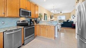 A modern kitchen with wooden cabinets, stainless steel appliances, and a central island. - Ginger Mermaid / 916 E Dolphin Drive (Oak Island)