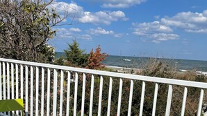A balcony with a white railing, a green and blue folding table, and chairs.