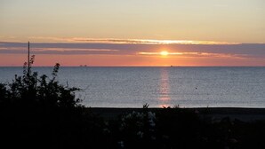 Auringonlasku tyynen meren yllä, kauempana näkyy laiva.