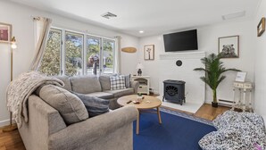 A living room with a sofa, a coffee table, a fireplace, a television, and a large window. - SAUNA & GAME ROOM- Pet friendly! Close to Dock Square and the Beach! (Kennebunk)