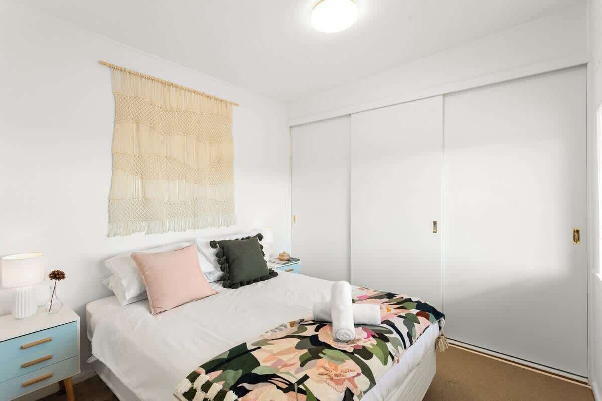 Une chambre à coucher comprenant un lit, une table de chevet, une lampe et une grande armoire.