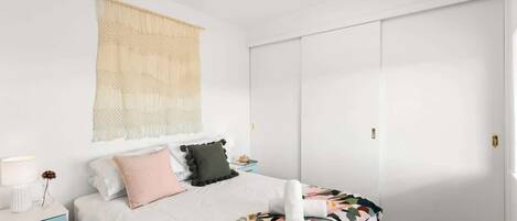 Une chambre à coucher comprenant un lit, une table de chevet, une lampe et une grande armoire.