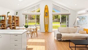 Un luminoso espacio de sala de estar integrado con cocina, comedor y un amplio ventanal con vistas a un jardín.