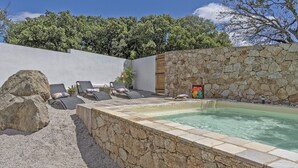 A spa area with a hot tub, lounge chairs, and a stone wall. - Maison Neuve 6 Personnes Monticello (Monticello)