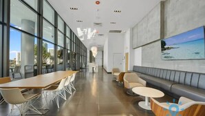 Een moderne hotellobby met een lange receptiebalie, een zithoek en grote ramen met uitzicht op de skyline.