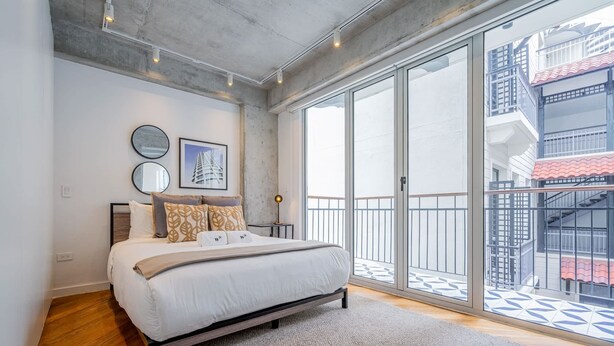 Een moderne slaapkamer met een groot bed, een uitzicht op een balkon en een stadsgezicht.