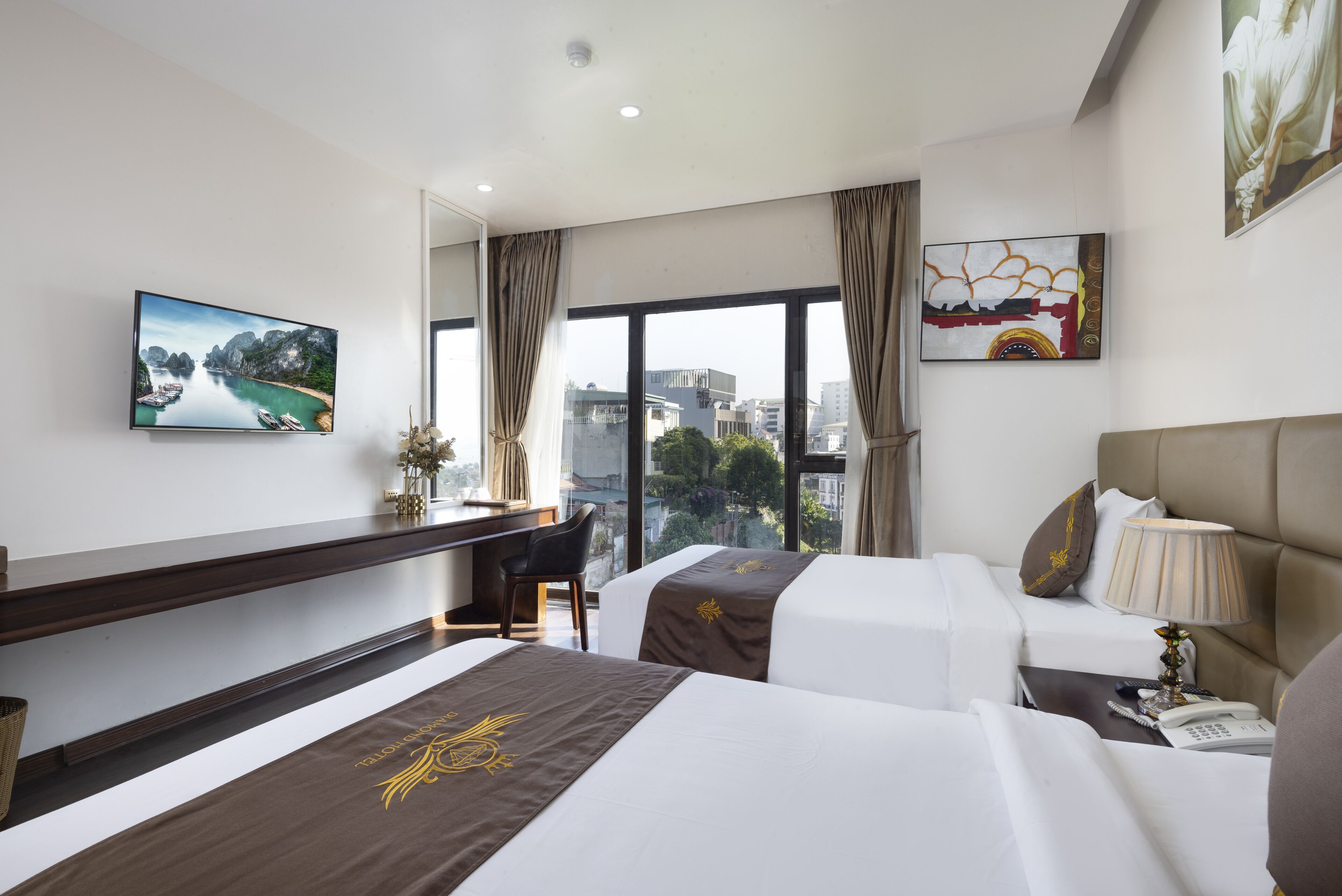 Habitación de hotel con dos camas, un escritorio, una silla, un televisor y un ventanal con vista a la ciudad.