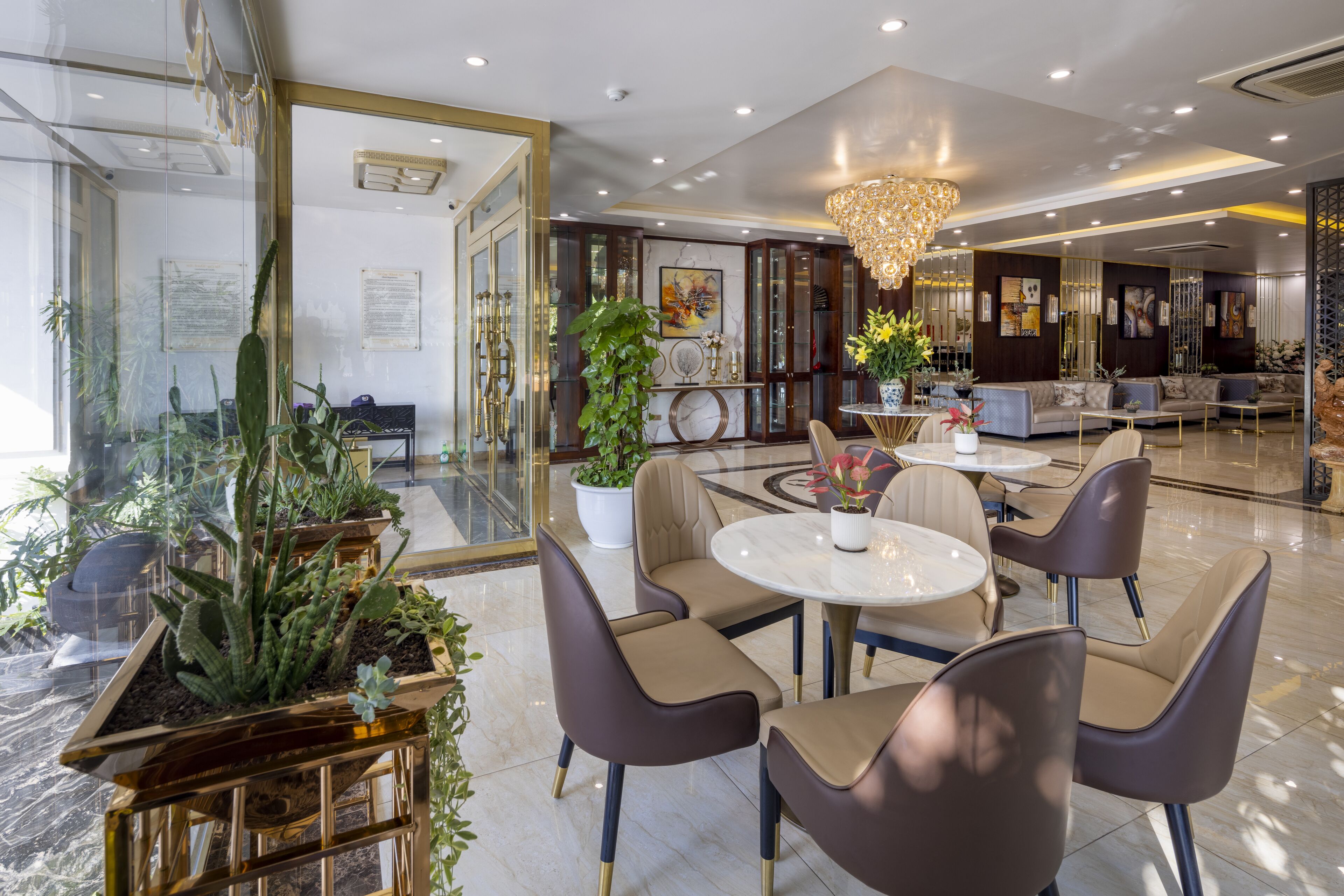 A modern hotel lobby with a round table, comfortable seating, and decorative plants.