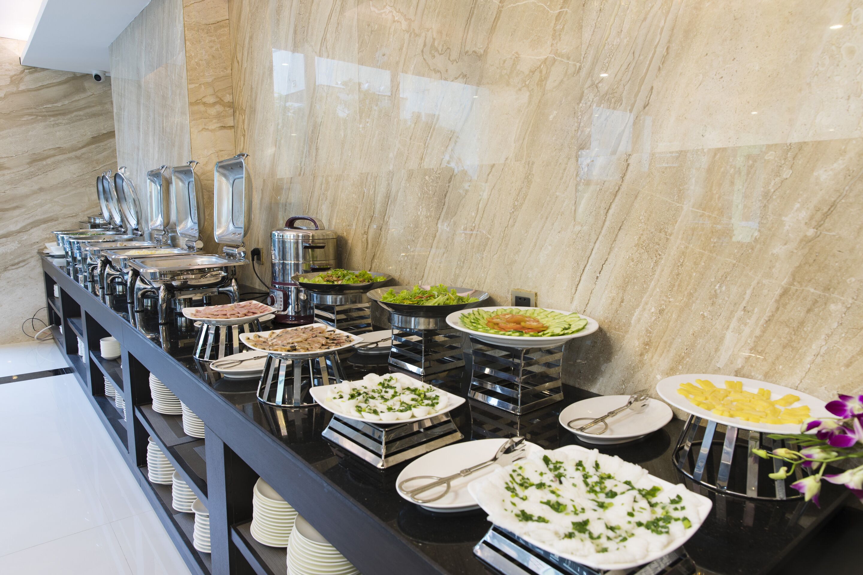 A buffet setup with various food stations and utensils.