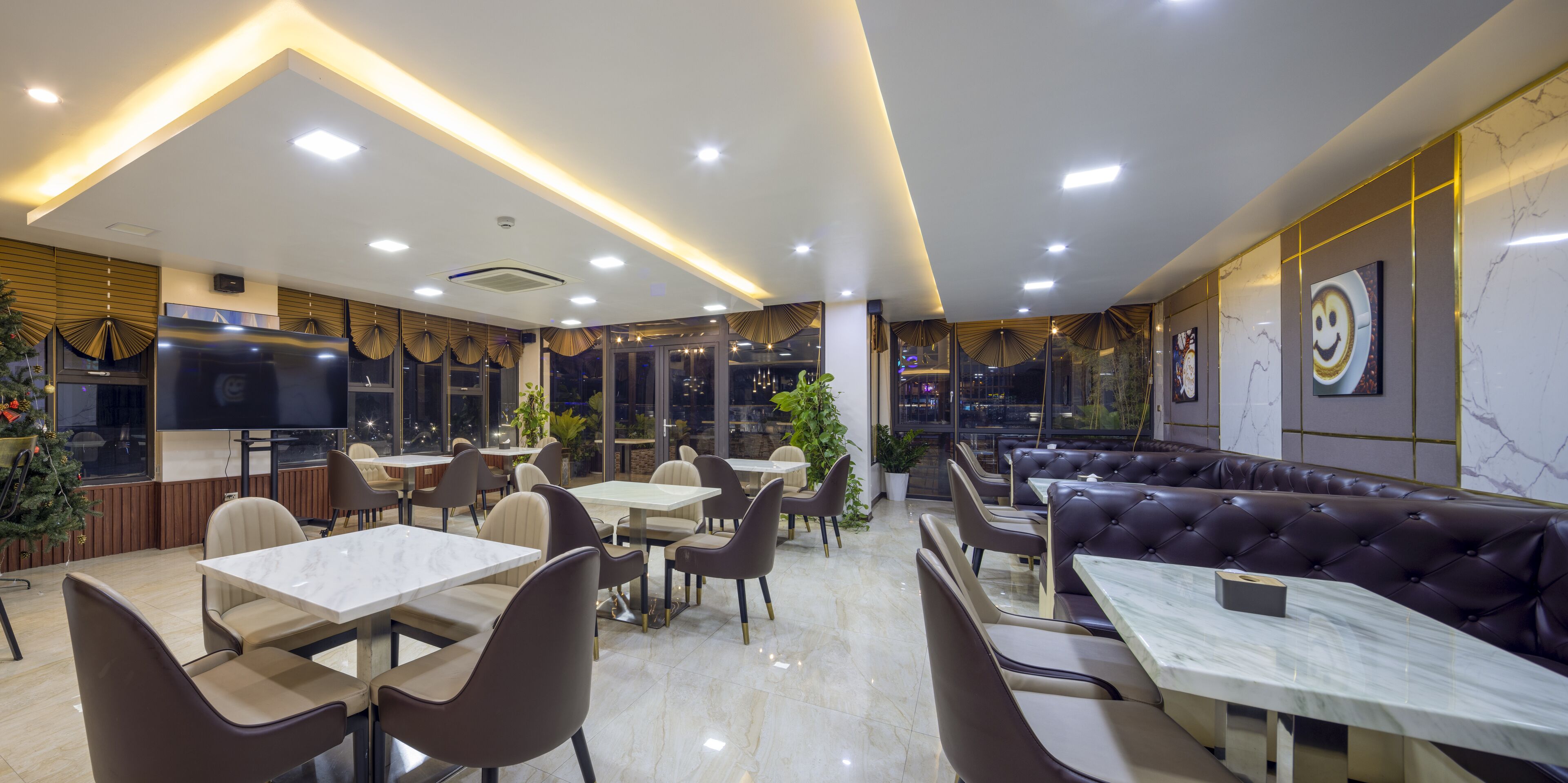 A modern restaurant with marble flooring, leather seating, and a large TV screen.