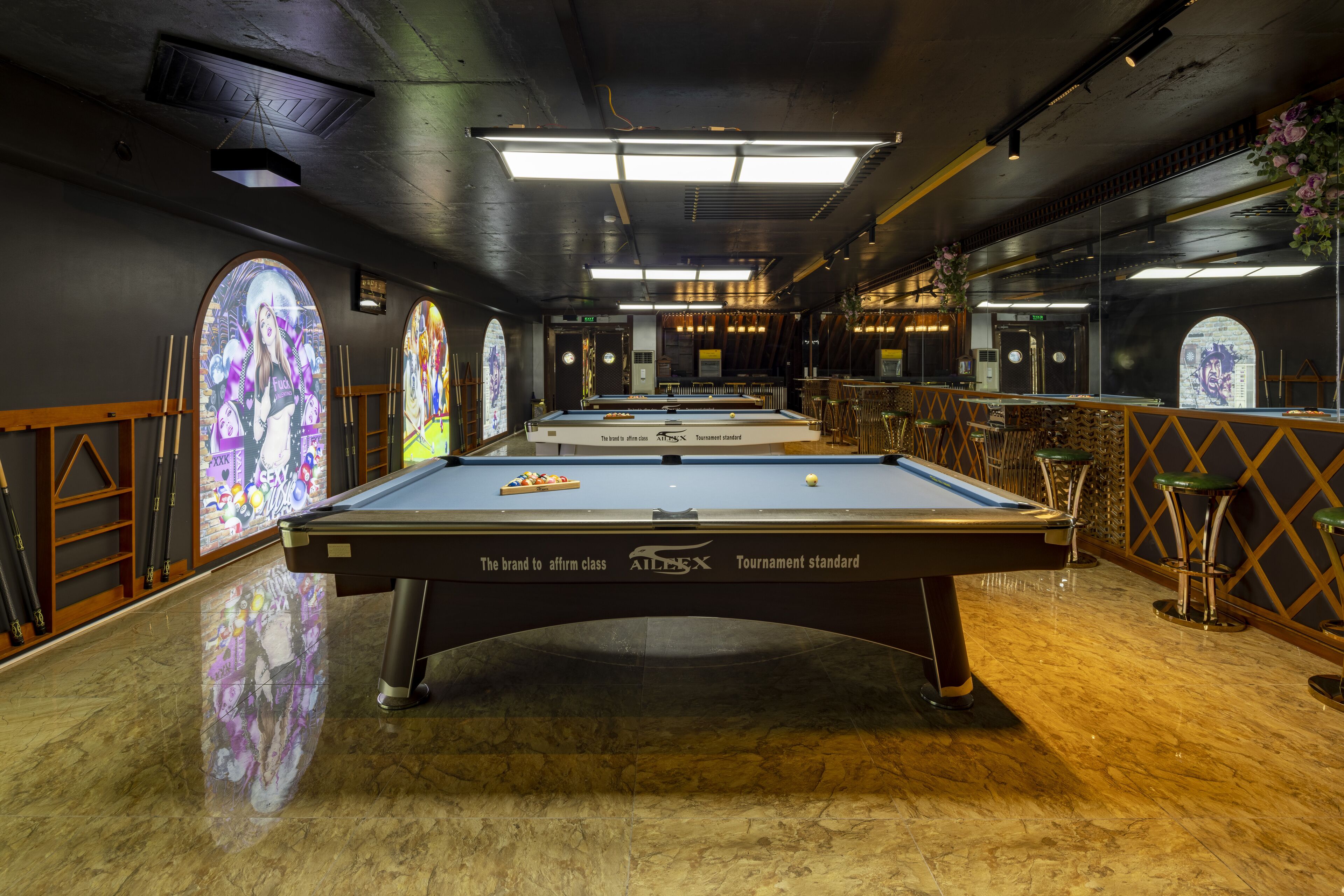 Una mesa de billar en una sala con ventanales arqueados y una zona de bar.