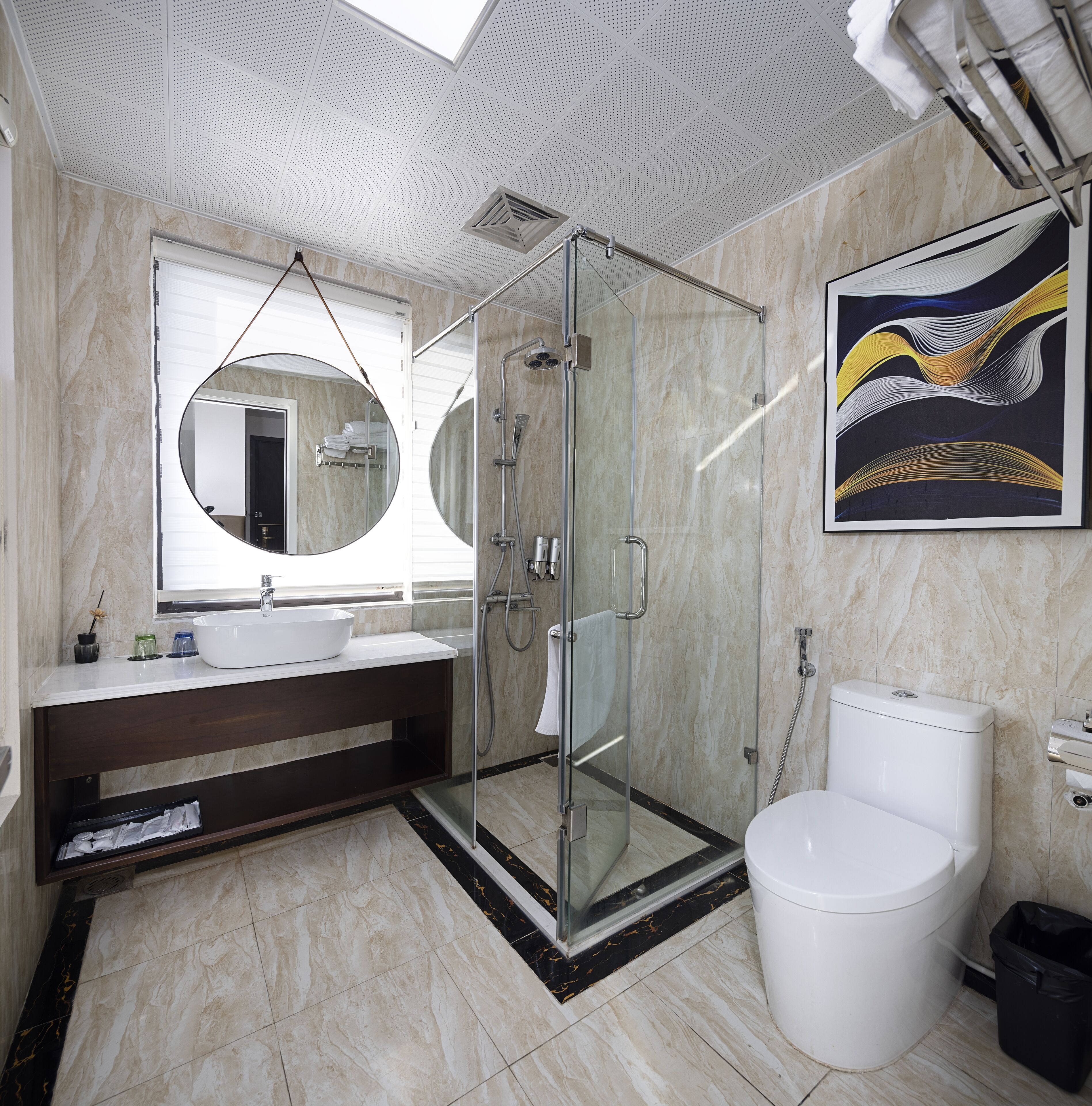 A modern bathroom with a glass-enclosed shower, a large mirror, and a white toilet.