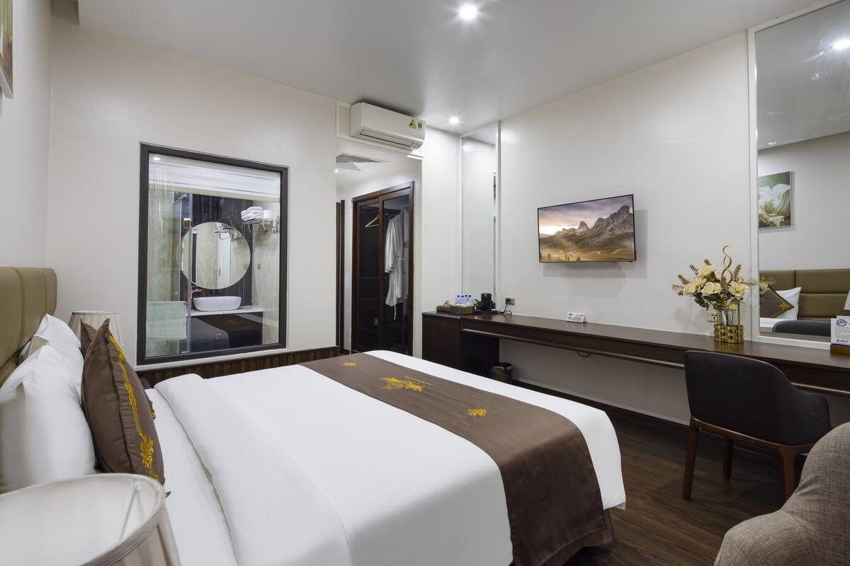 Una habitación de hotel con una cama, un escritorio, una silla, un espejo y un cuadro en la pared.