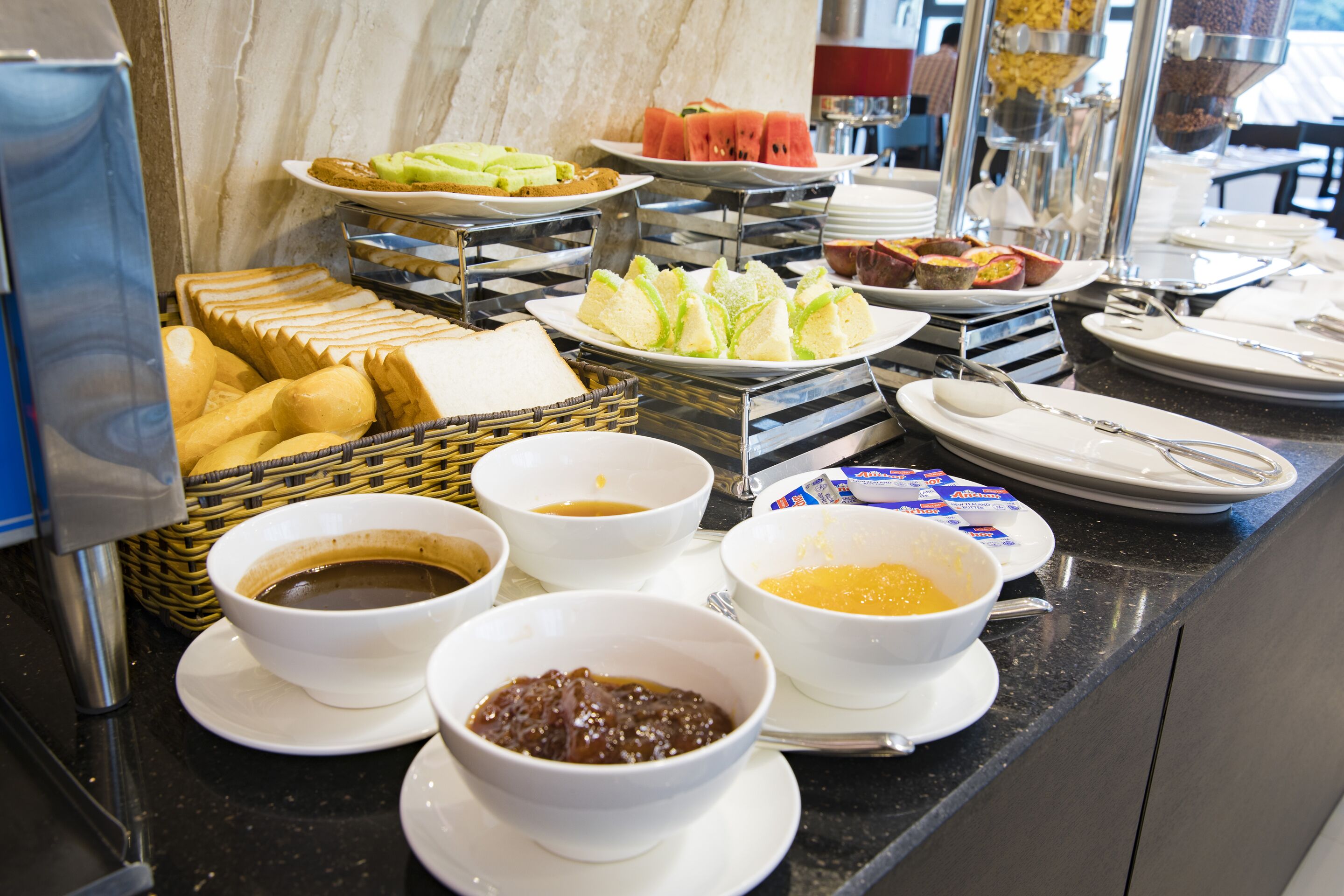 Un buffet proposant une variété d’aliments, notamment du pain, des fruits et des boissons.