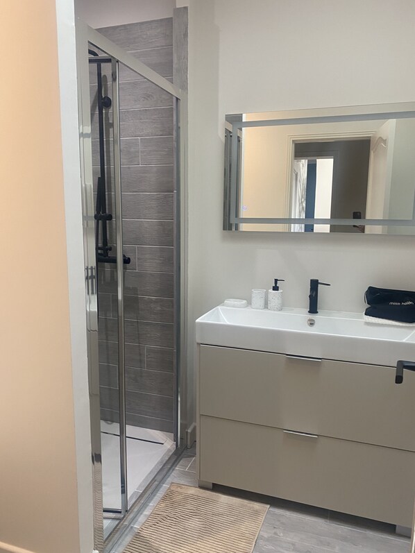 A modern bathroom with a glass shower enclosure, a white sink with a black faucet, and a mirror above the sink. - Magnificent Villa with heated pool in Saint Rémy de Provence (Saint-Rémy-de-Provence)