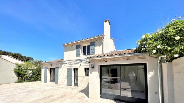 A modern house with a tiled patio, a large sliding glass door, and a chimney.