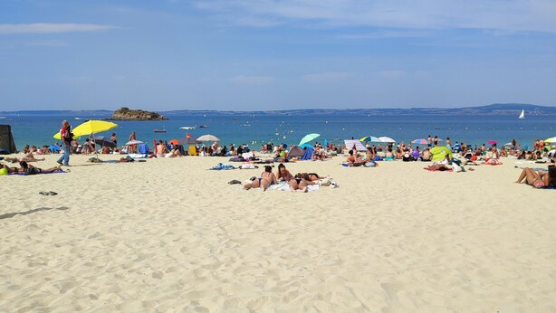 A sandy beach with people sunbathing and walking.
