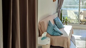A room with a bed, a small table, a chair, and a view of the outdoors.