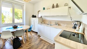 Een moderne keuken met witte kastjes, een houten aanrecht en een eethoek met een tafel en stoelen.