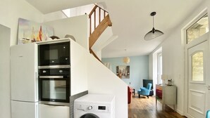 Een kleine keuken met een ingebouwde oven, magnetron en wasmachine.