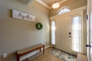 A hallway with a bench, a door, a wall-mounted sign, and a wreath.