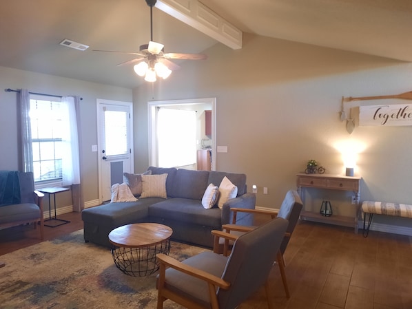 A living room with a sectional sofa, a round coffee table, and a ceiling fan.