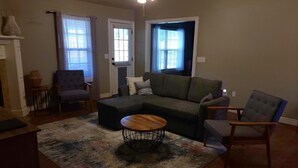 A living room with a sectional sofa, a round coffee table, and two armchairs. - Peaceful 3BR Base • Close to NWA Events & Trails. Secure Garage and Jetted Tub. (Pea Ridge)