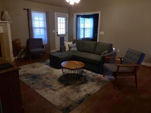 A living room with a sectional sofa, a round coffee table, and two armchairs.