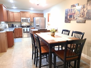 A kitchen with wooden cabinets, stainless steel appliances, and a dining area with a table and chairs.