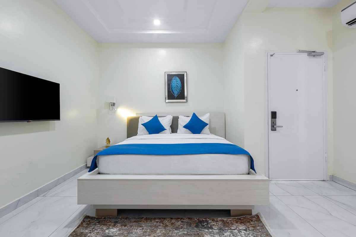 A modern bedroom with a bed, a mounted TV, and a door.