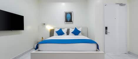 A modern bedroom with a bed, a mounted TV, and a door.