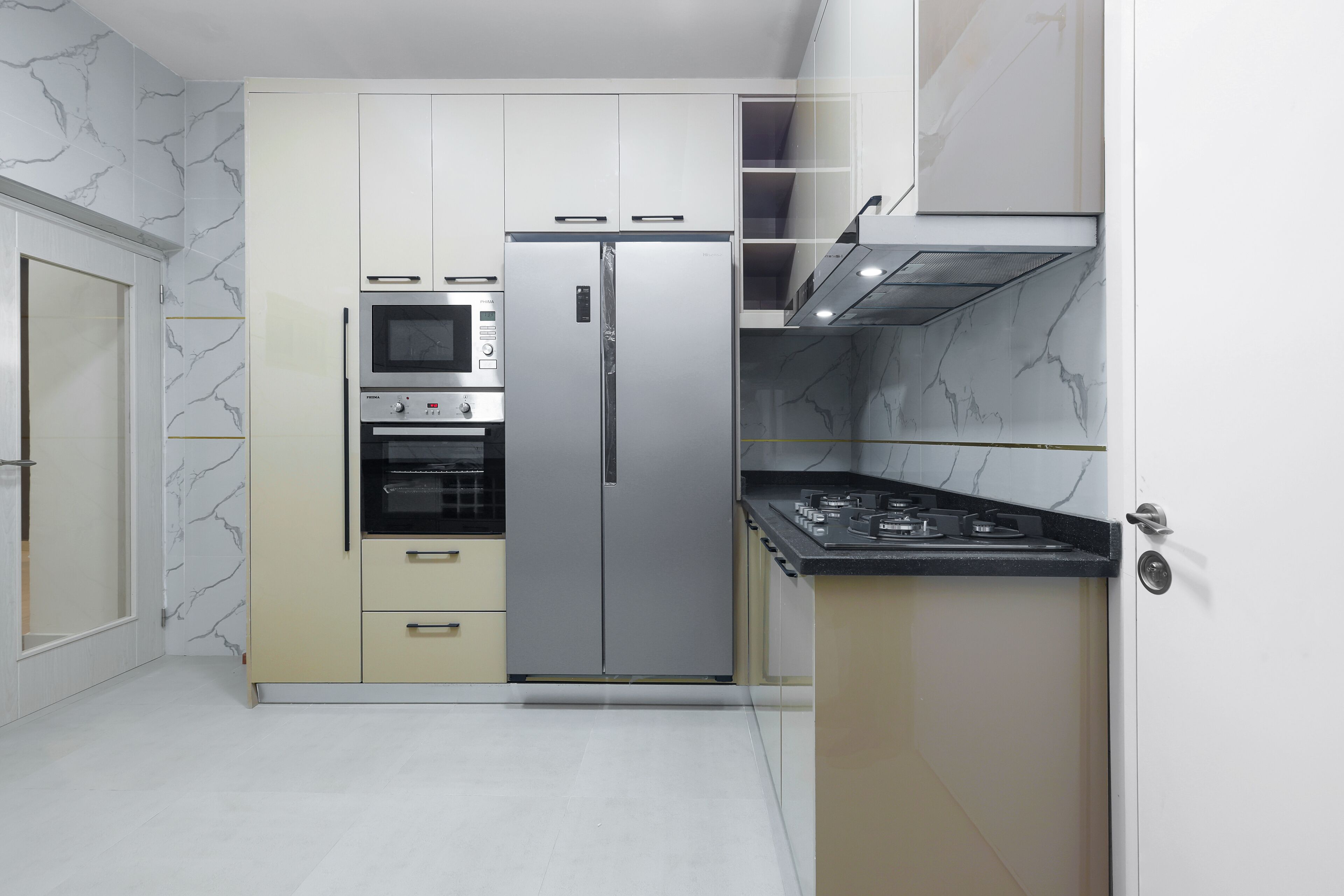 Una cucina compatta con forno a incasso, microonde e frigorifero in acciaio inossidabile.