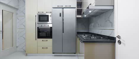 Cocina compacta con horno integrado, microondas y refrigerador de acero inoxidable.