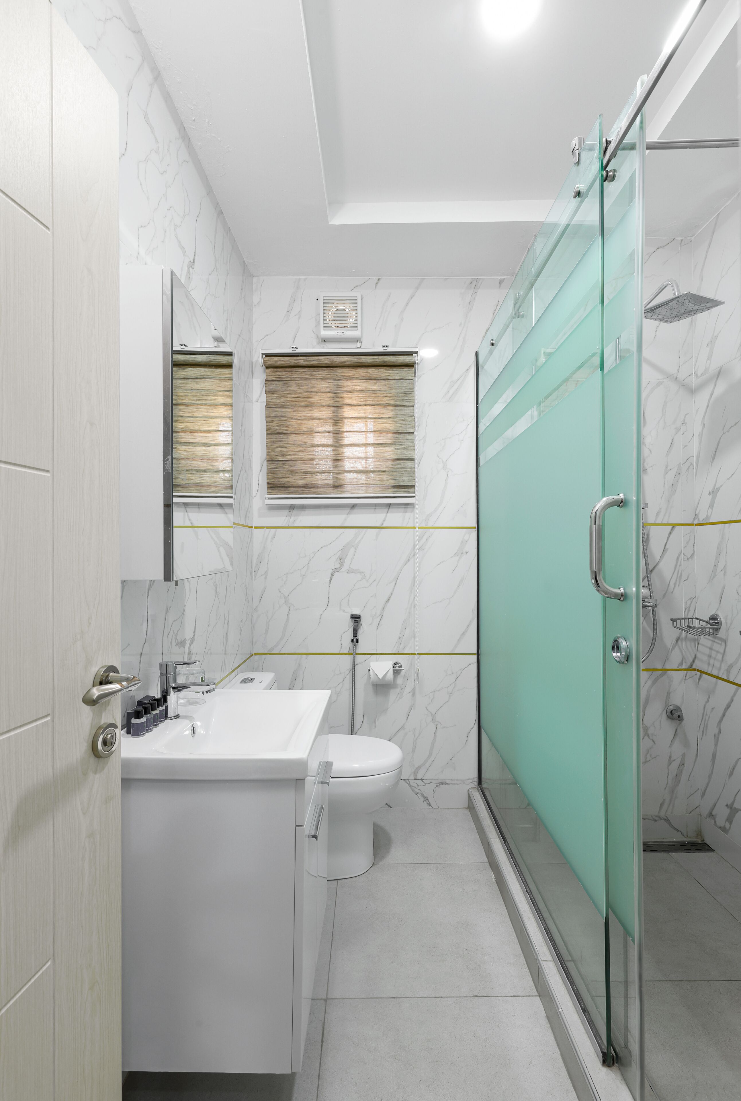 A bathroom with a glass-enclosed shower, a white sink, and a toilet.