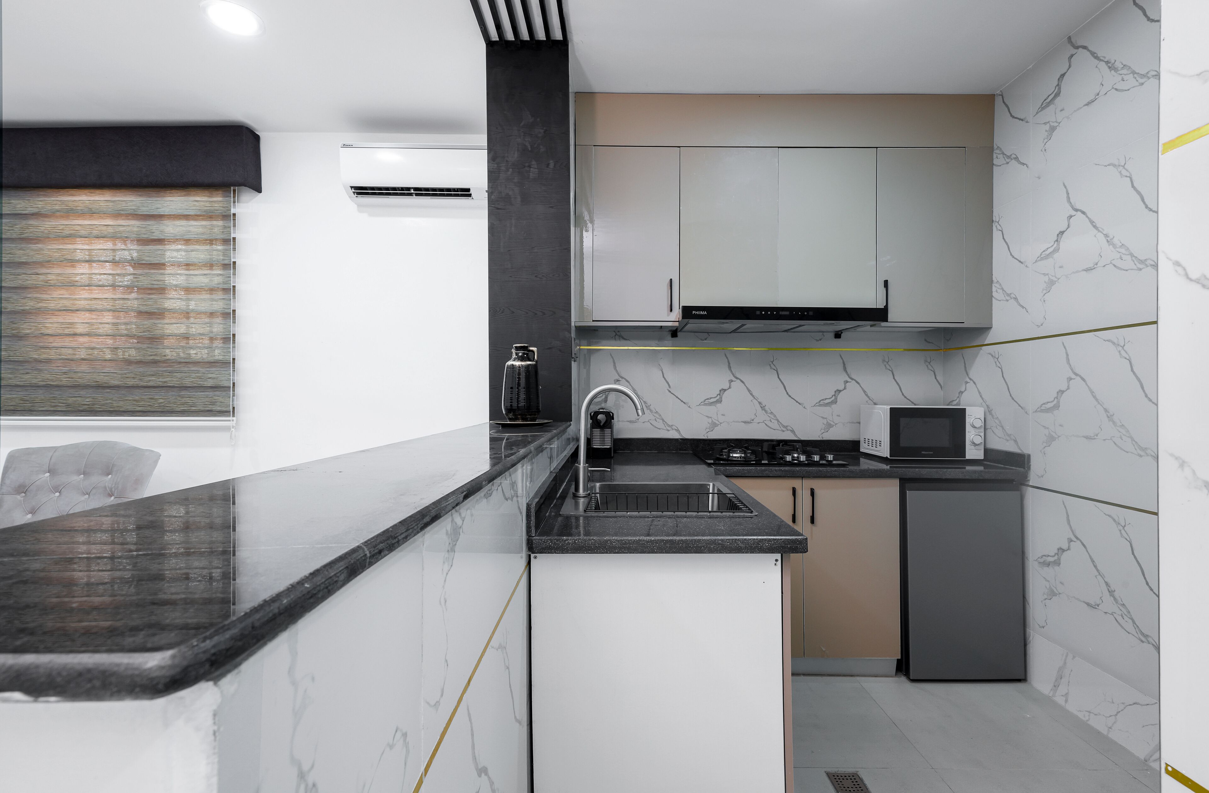 A compact kitchen with a marble backsplash, a built-in microwave, and a gas stove.