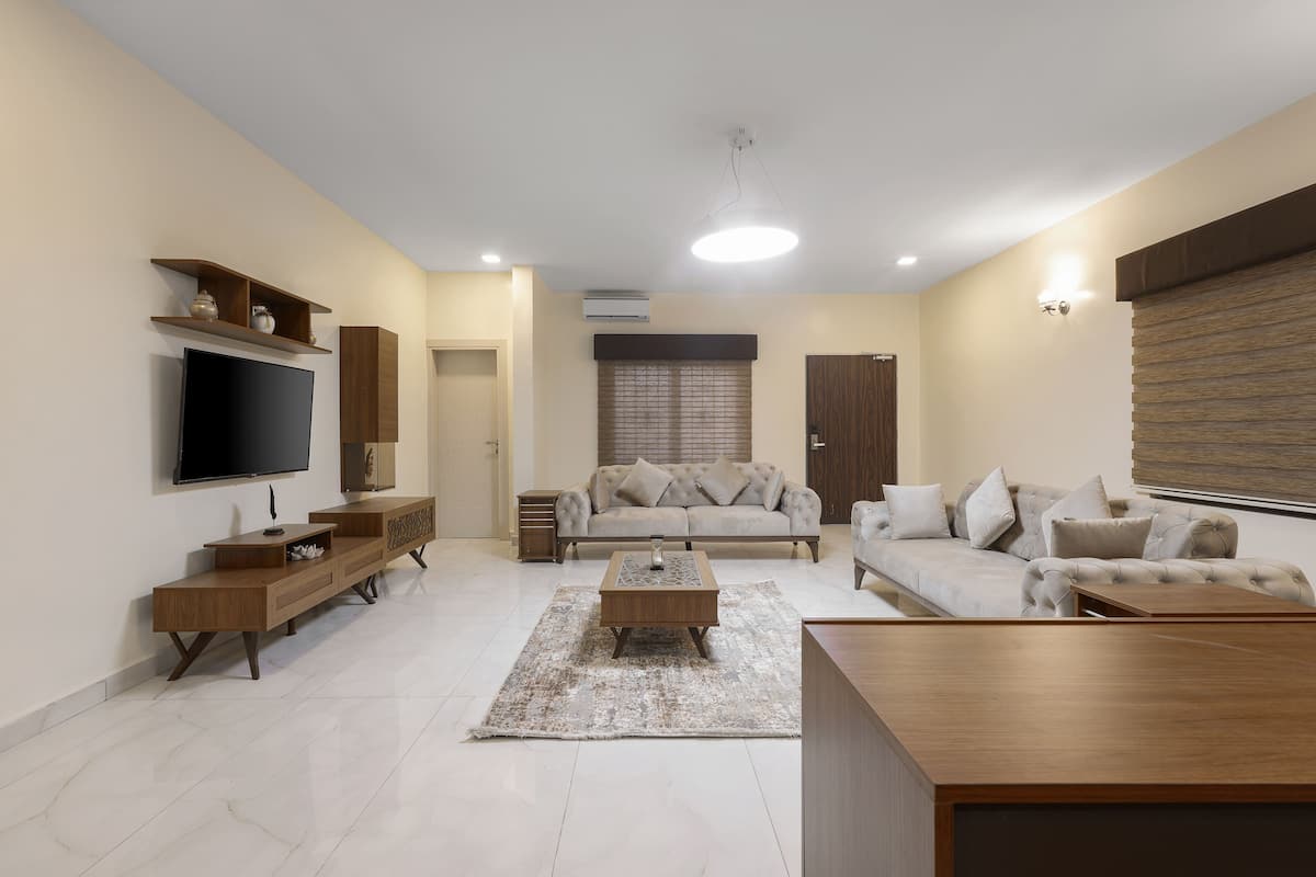 A modern living room with a flat-screen TV, two sofas, a coffee table, and a wooden TV stand.